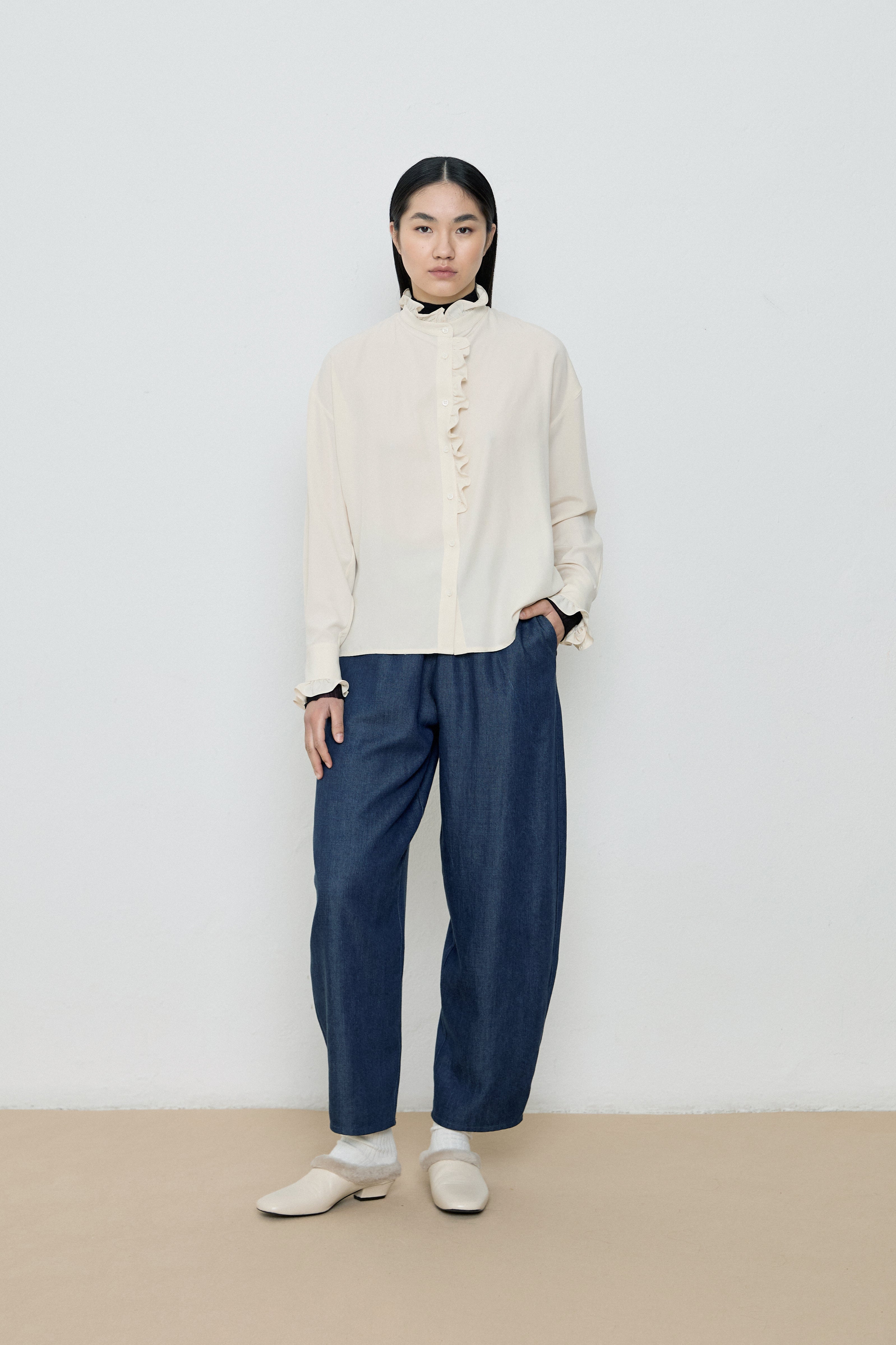 Person wearing a white shirt and blue pants against a plain background