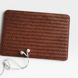 Brown woven leather wallet with earphones on a light gray surface