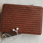 Brown woven leather wallet with earphones on a light gray surface
