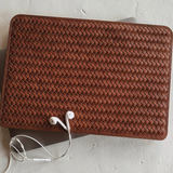Brown woven leather wallet with earphones on a light gray surface