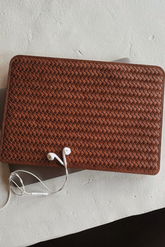 Brown woven leather wallet with earphones on a light gray surface