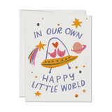 Greeting card with colorful illustration of a baby in a stroller, planet, and rainbow with text 'In our own happy little world' on a white background.