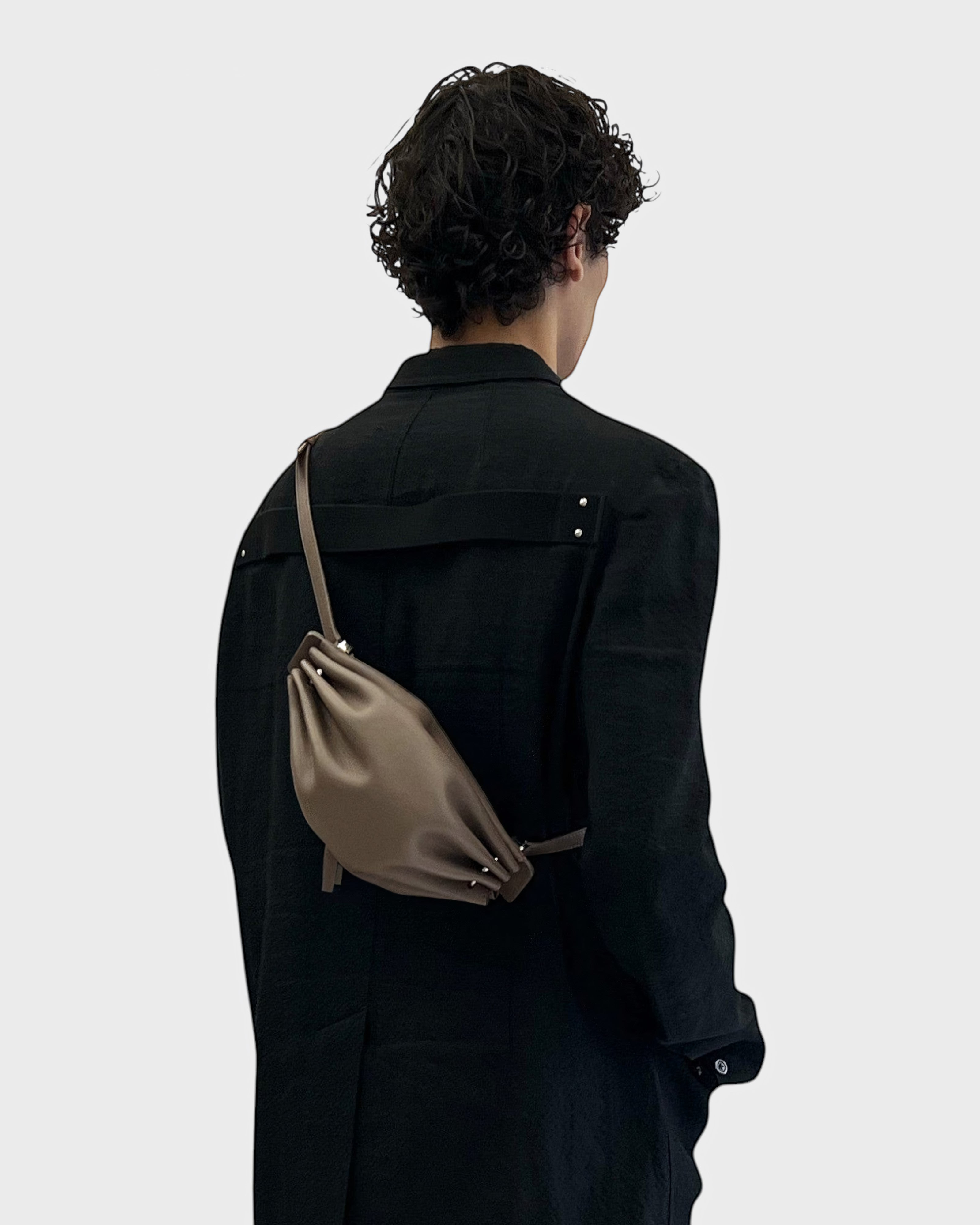 JONES + CO Bon-Bon taupe leather shoulder bag with metal clasp worn across the back by a person in a black jacket