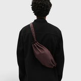 JONES + CO Bon-Bon M wine leather crossbody bag worn by a person in a black jacket, showing back view