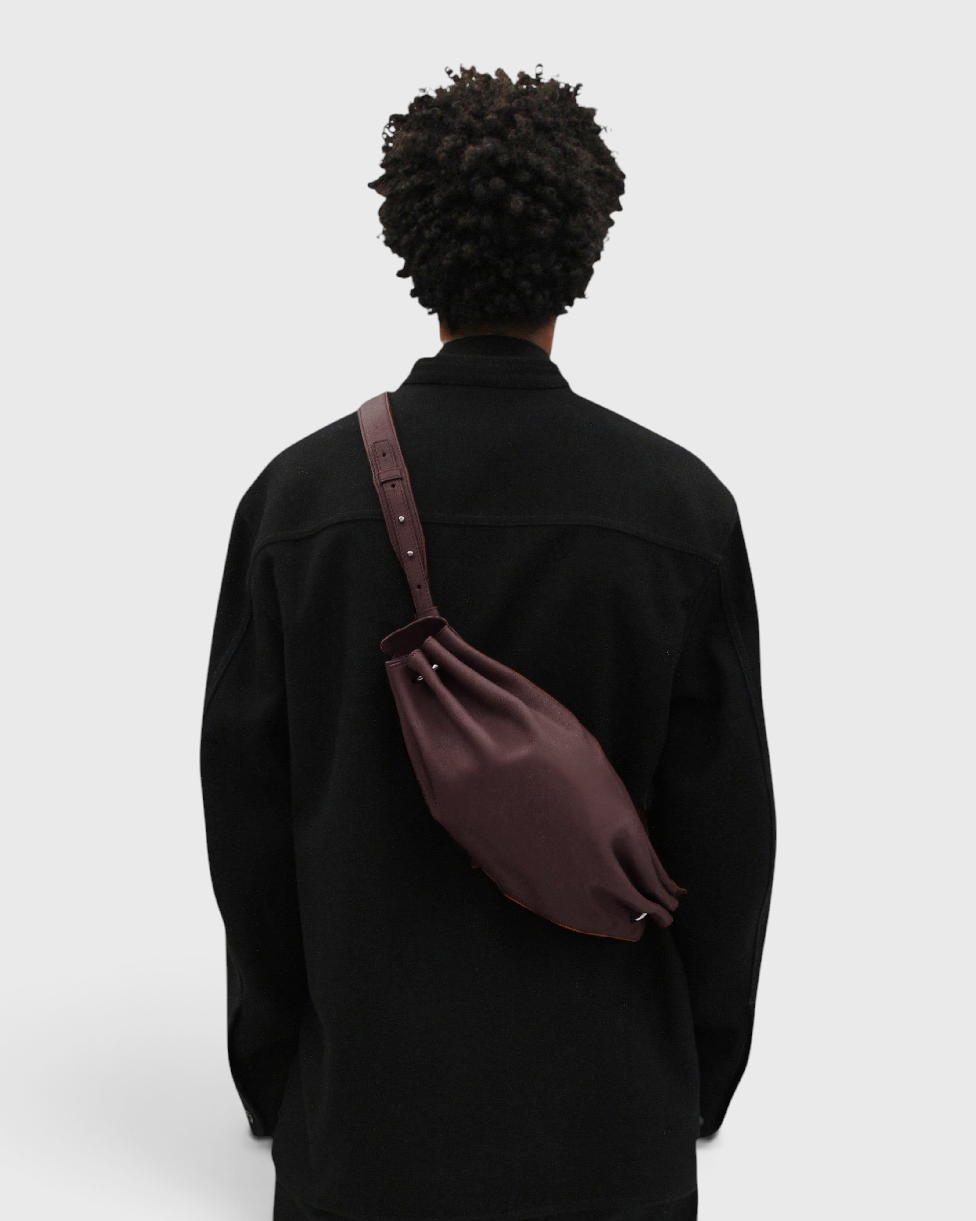 JONES + CO Bon-Bon M wine leather crossbody bag worn by a person in a black jacket, showing back view