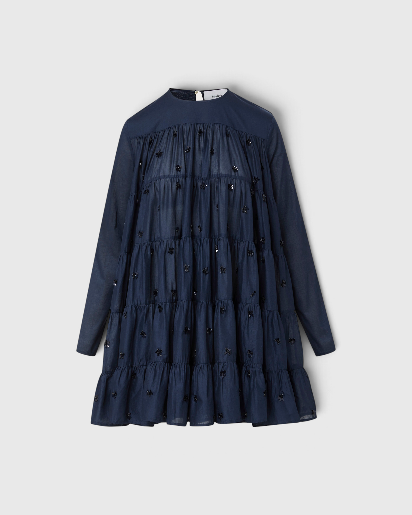 Merlette Soliman Dress in Navy — flat product shot of the tiered cotton voile dress with tonal floral embroidery, long sleeves and round neck