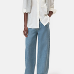 Person wearing Oversized button up in white and light blue pants on a white background