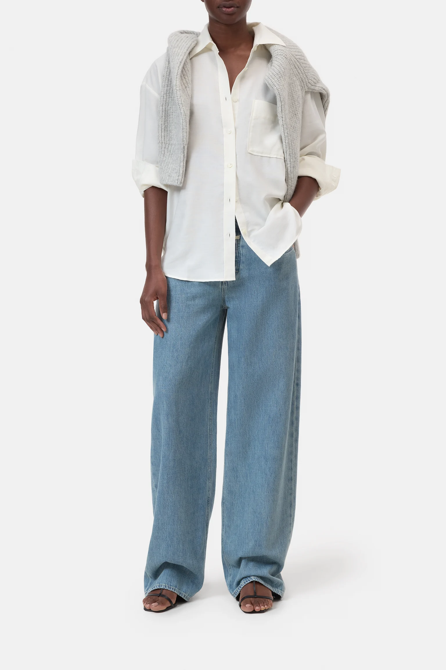Person wearing Oversized button up in white and light blue pants on a white background