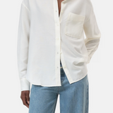 Person wearing a white button-up shirt and blue jeans on a white background