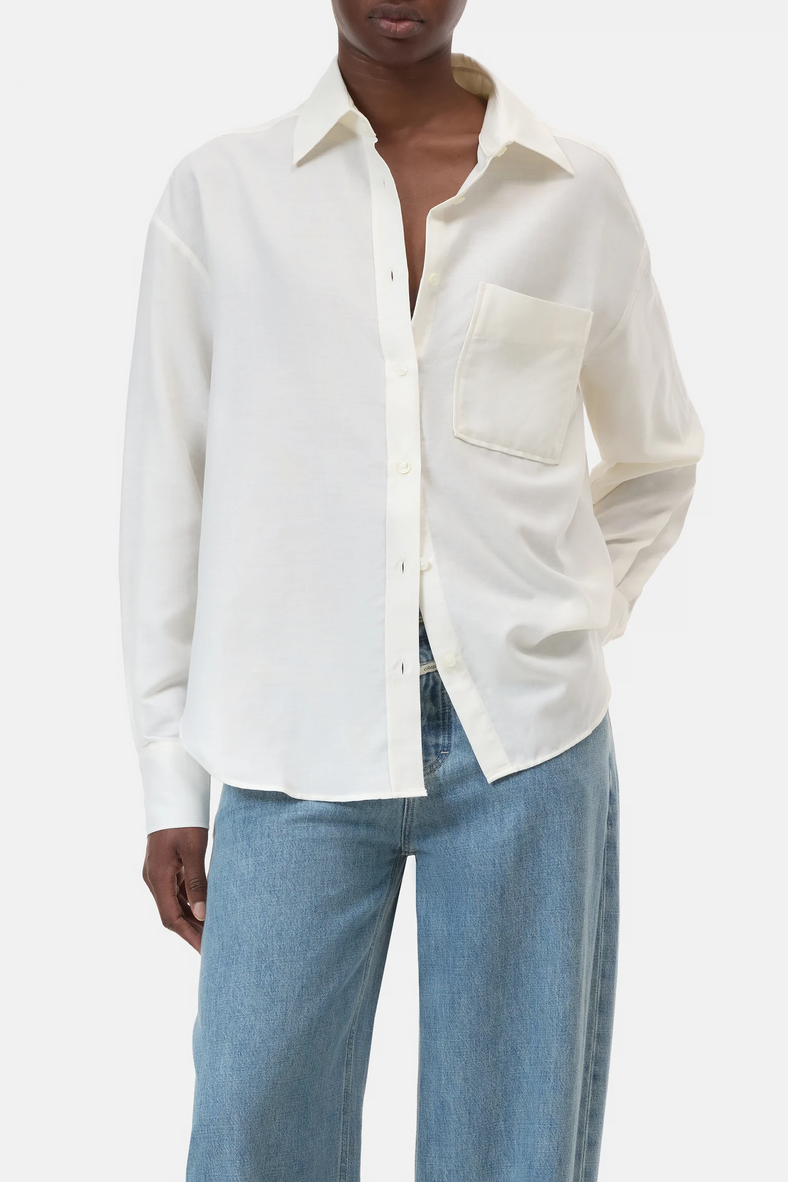 Person wearing a white button-up shirt and blue jeans on a white background