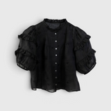 JONES + CO black ramie-cotton Evi blouse with ruffled stand collar, pintucked yoke, and puffed sleeves with trim.
