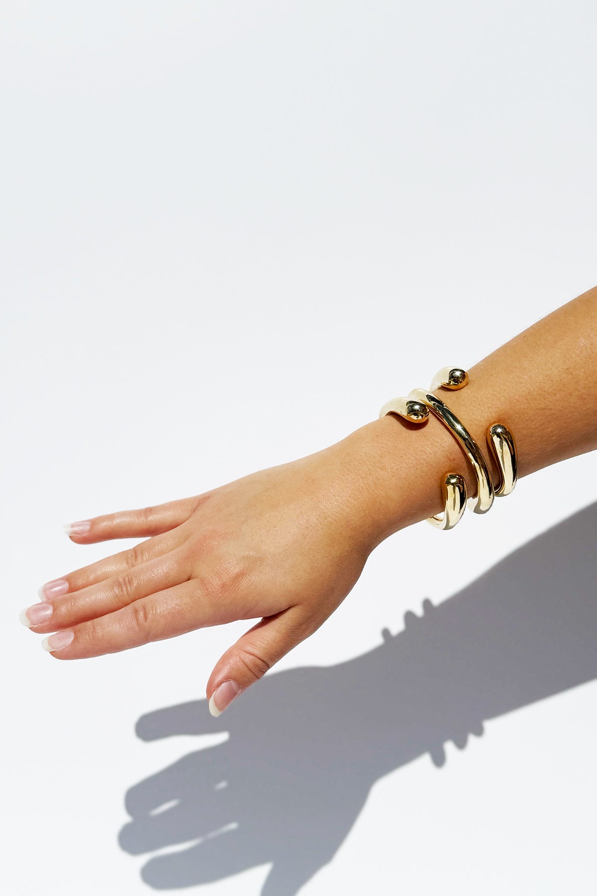 Hand wearing a gold bracelet on a white background
