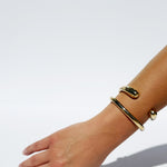 Hand wearing a gold bracelet on a white background