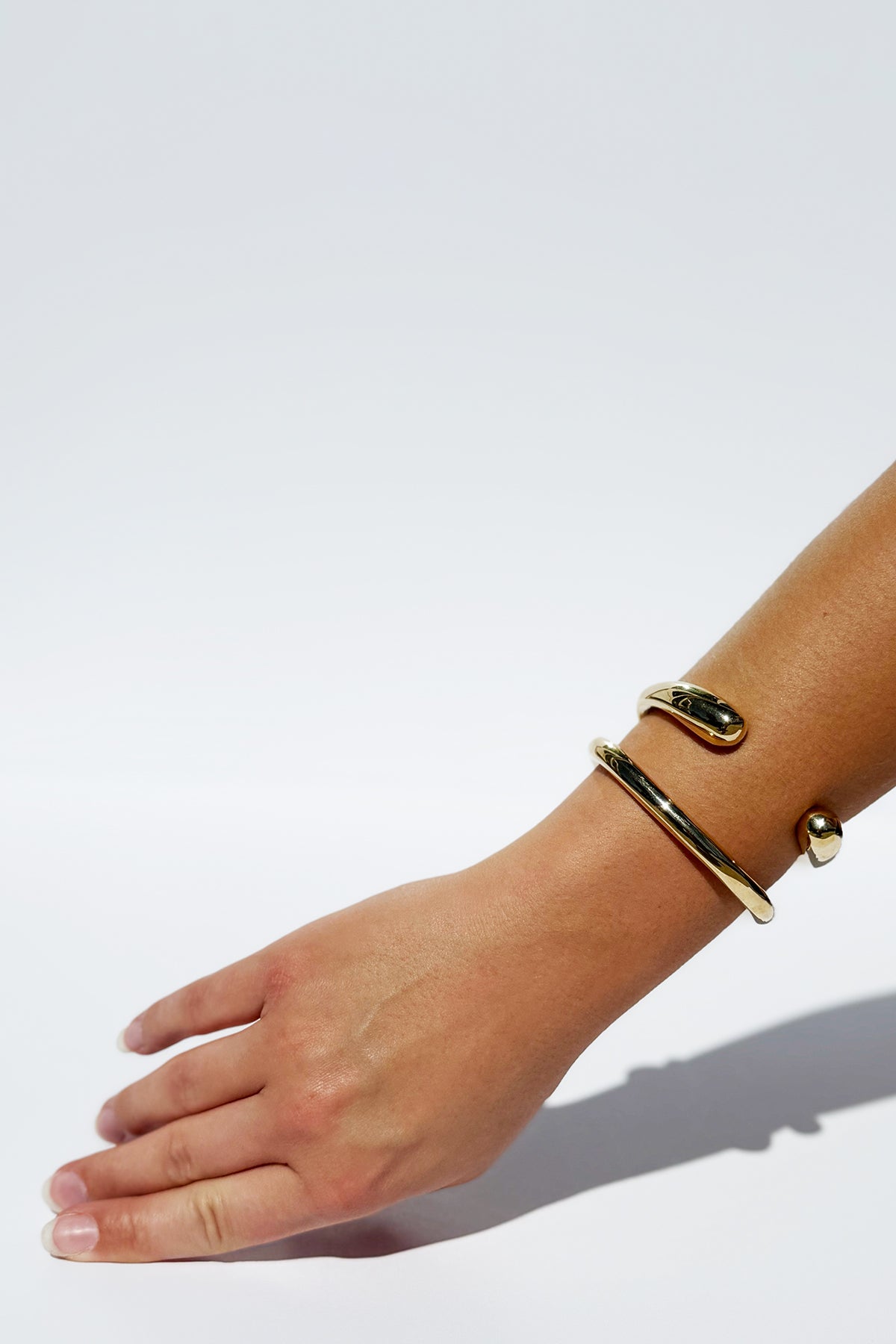 Hand wearing a gold bracelet on a white background