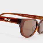 close up logo view of Romi Sunglasses - Transparent Rust