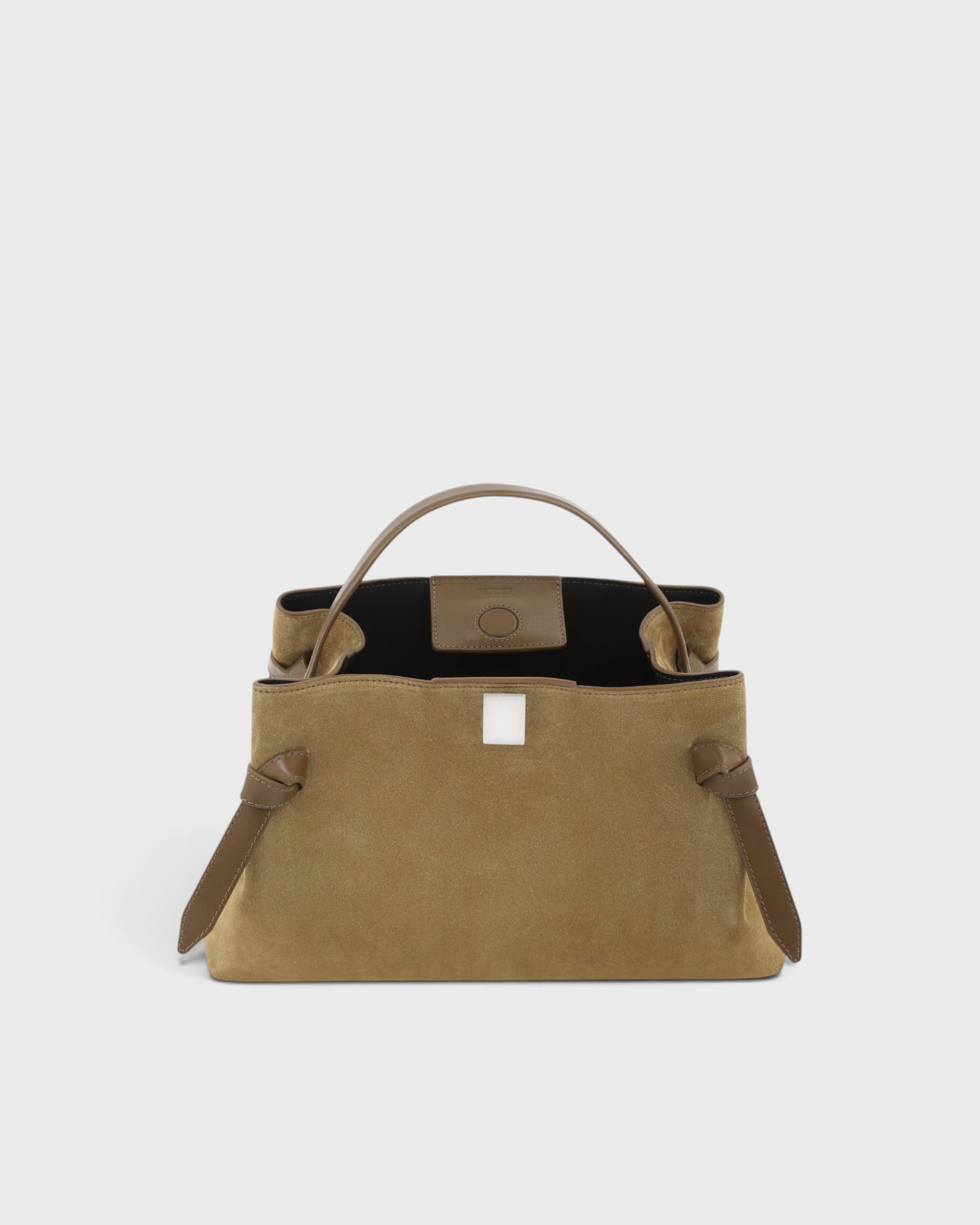 JONES + CO Gyoza pouch in fennel suede with a structured handle and elegant knot details on a neutral background