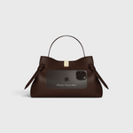 JONES + CO Gyoza Sierra embossed brown leather pouch with gold hardware, shown with an iPhone 16 Pro Max for scale.