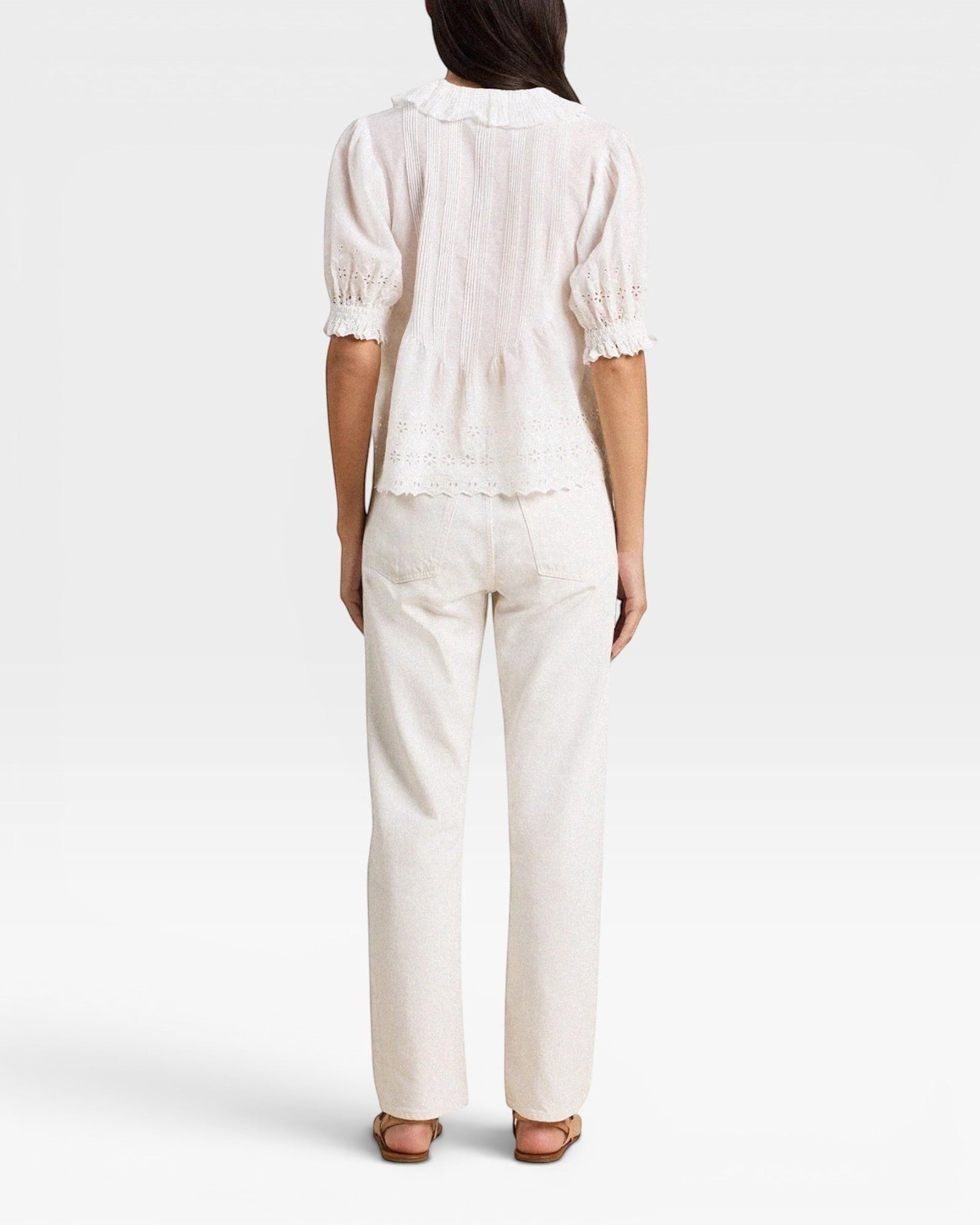 Person wearing a white blouse and pants on a plain background