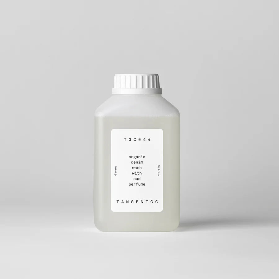 Bottle of organic denim wash with oud perfume by Tangent GC on a light gray background