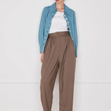 Person wearing a blue denim jacket, white shirt, brown pants, and beige shoes on a white background