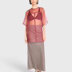 Model wearing JONES + CO Santander silk skirt in shadowline plaid with a sheer burgundy top and black strappy heels.