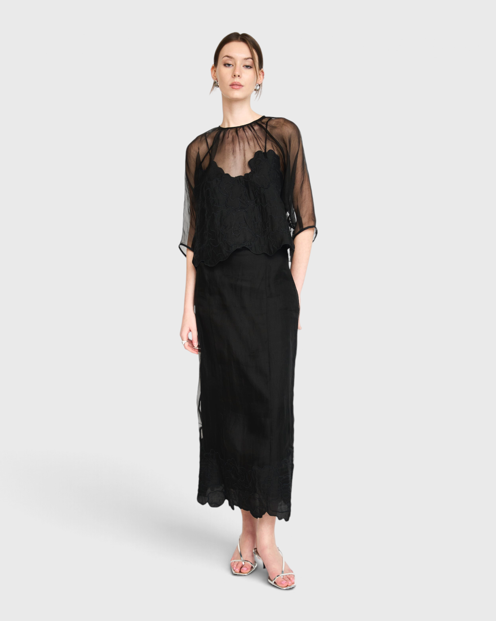 Model wearing JONES + CO black organza Bari top with delicate waterlily embroidery over a matching black slip dress.