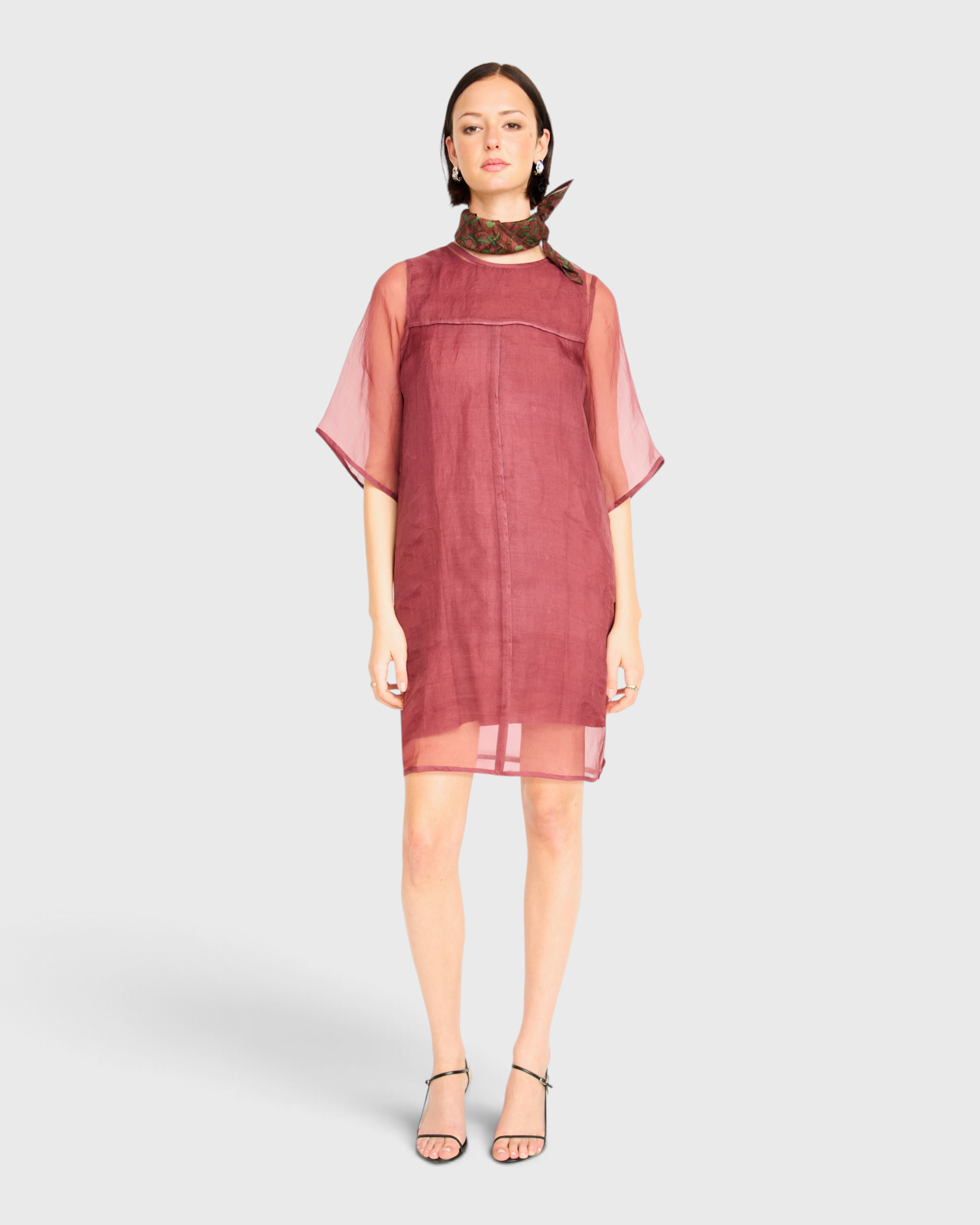 Model wearing a dark cerise JONES + CO Umbria organza dress with sheer short sleeves and a patterned neck scarf