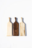 three wood cheeseboards, maple, walnut, and ambrosia maple, on white background