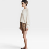 JONES + CO Pia Cotton Sweater in bone white, featuring a crew neckline and relaxed fit. Model wears shorts and flip-flops.