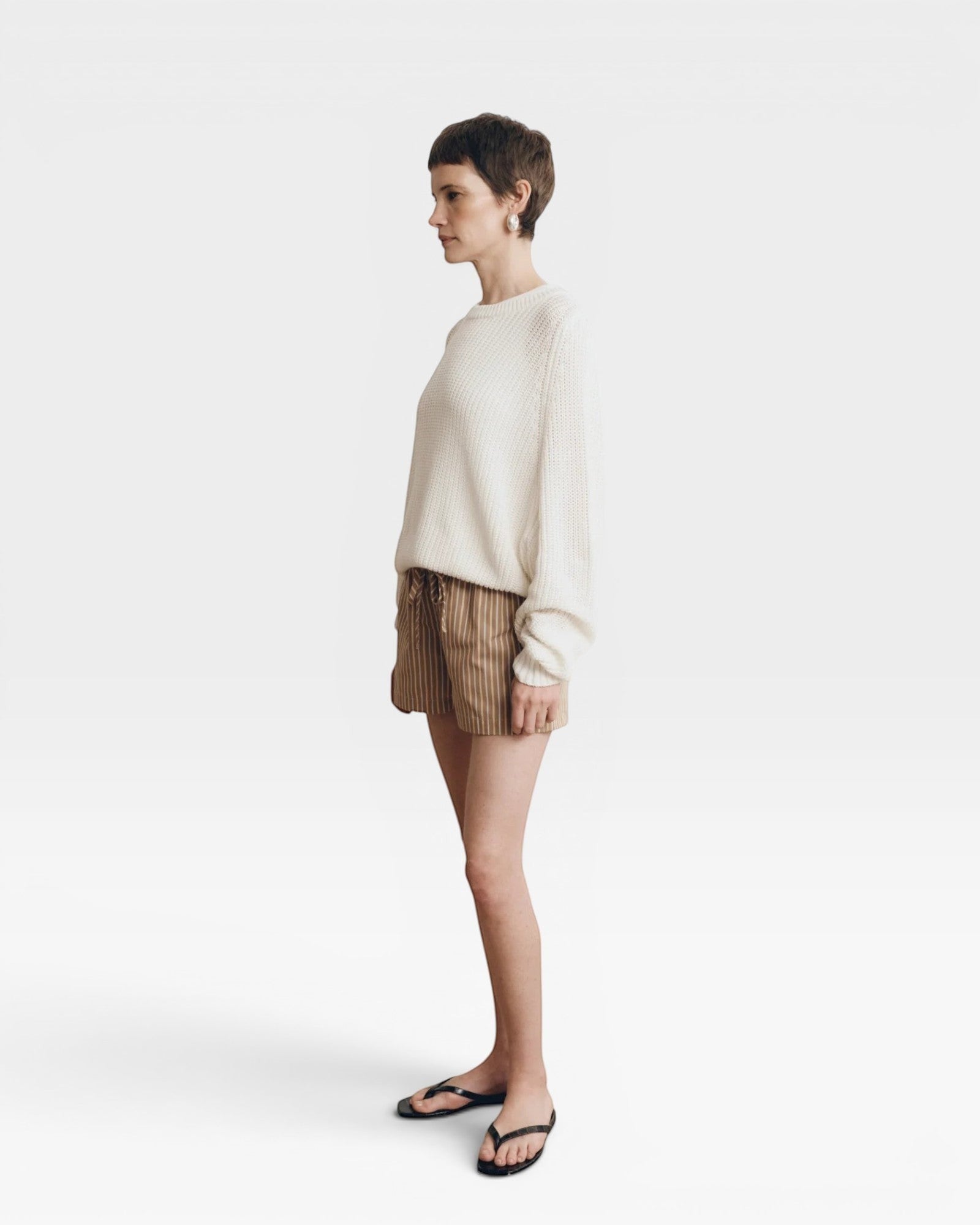 JONES + CO Pia Cotton Sweater in bone white, featuring a crew neckline and relaxed fit. Model wears shorts and flip-flops.