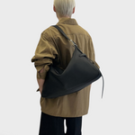 JONES + CO Rider M black leather shoulder bag with adjustable belt-style strap worn crossbody by a model
