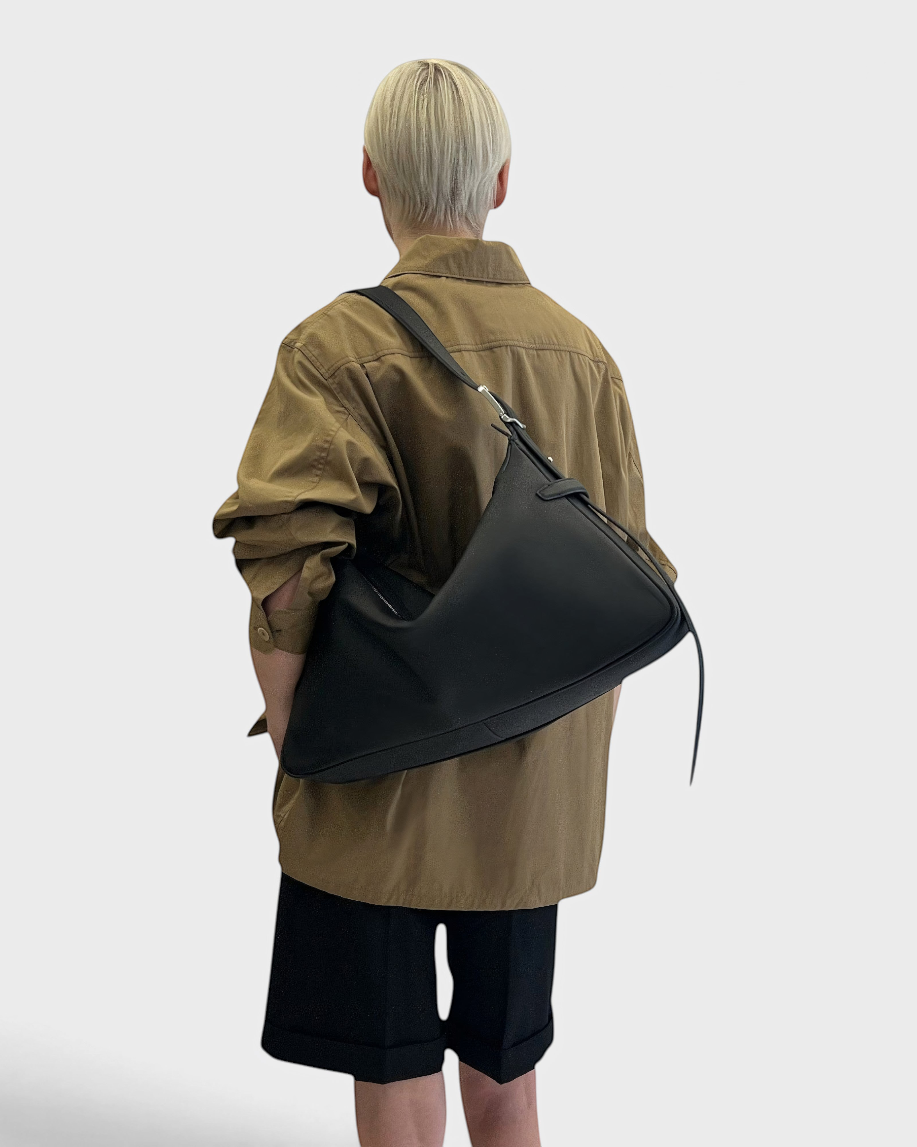 JONES + CO Rider M black leather shoulder bag with adjustable belt-style strap worn crossbody by a model