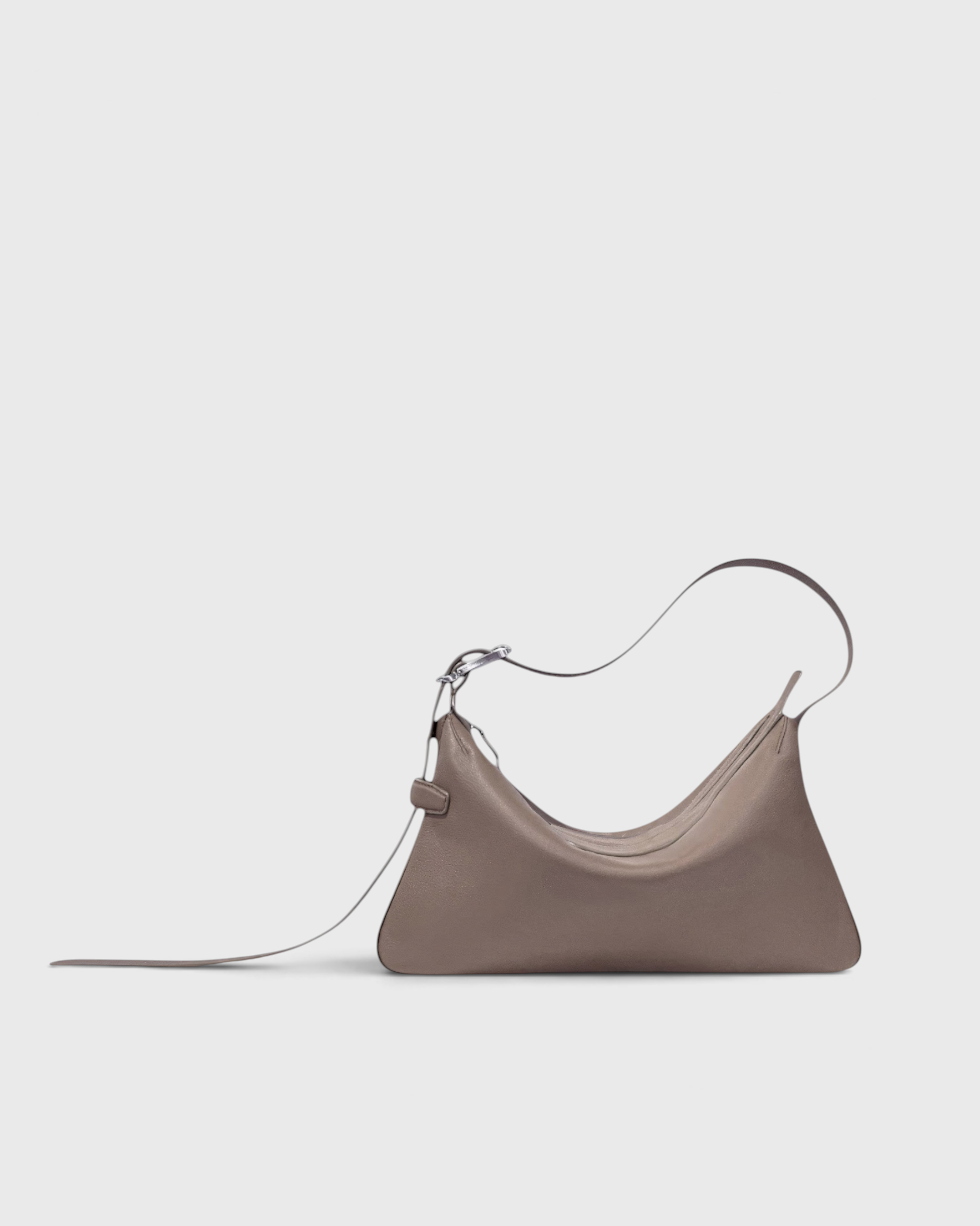 JONES + CO Rider S taupe leather bag with a unique skateboard rink shape and adjustable belt-style shoulder strap.