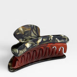 Marbled red and black hair clip on a white background
