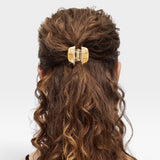 Person with wavy hair tied back with a decorative hair clip on a white background