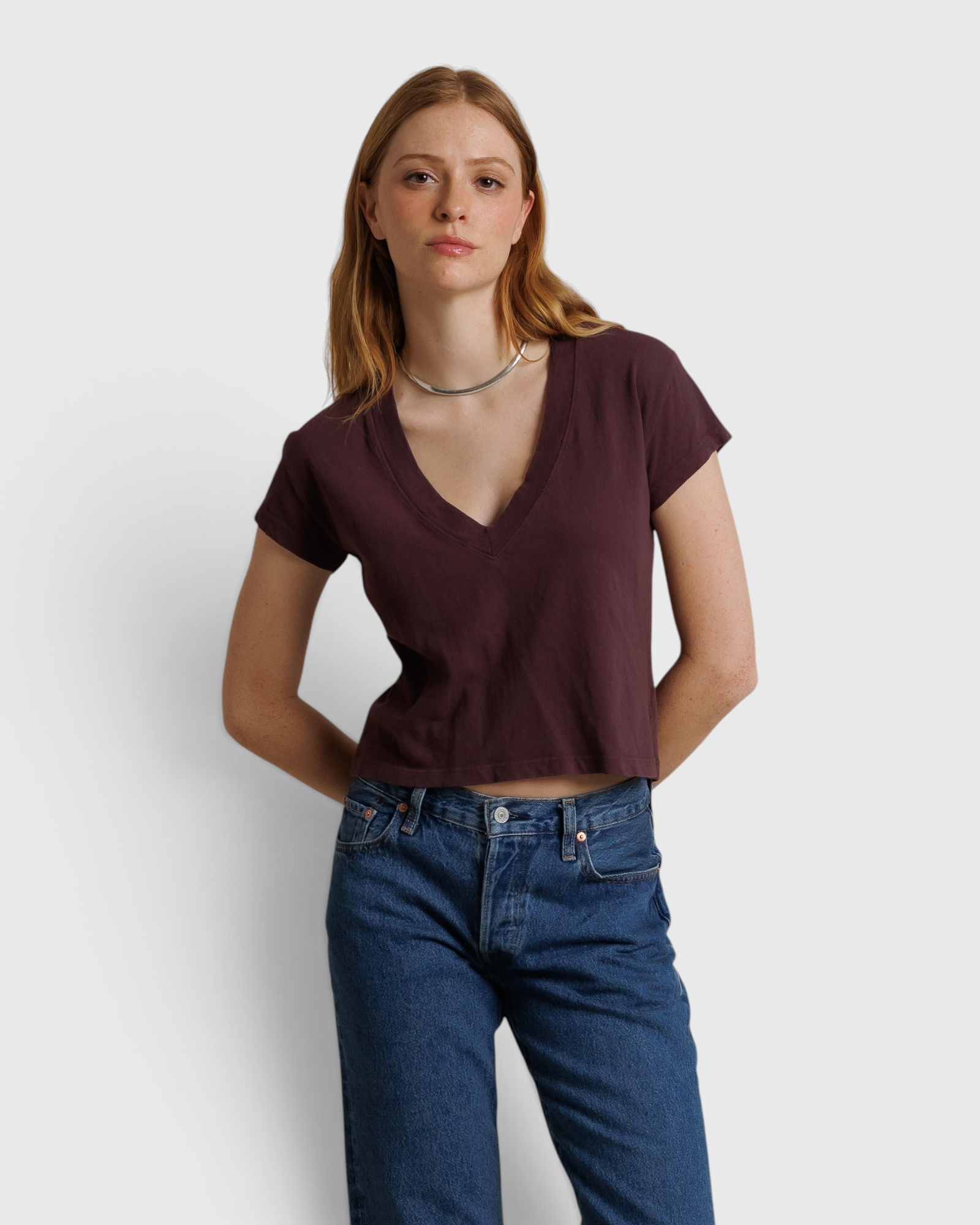 Model wearing a JONES + CO cherry lacquer recycled cotton V-neck cropped tee with blue jeans.