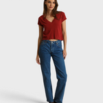 Model wearing a JONES + CO ruby red recycled cotton V-neck t-shirt with blue jeans and brown loafers
