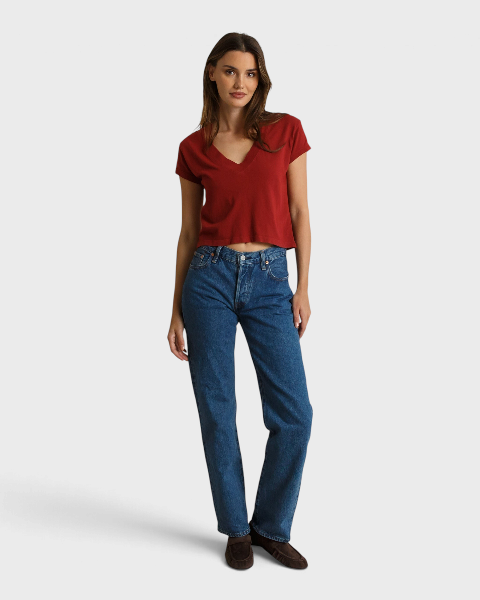 Model wearing a JONES + CO ruby red recycled cotton V-neck t-shirt with blue jeans and brown loafers