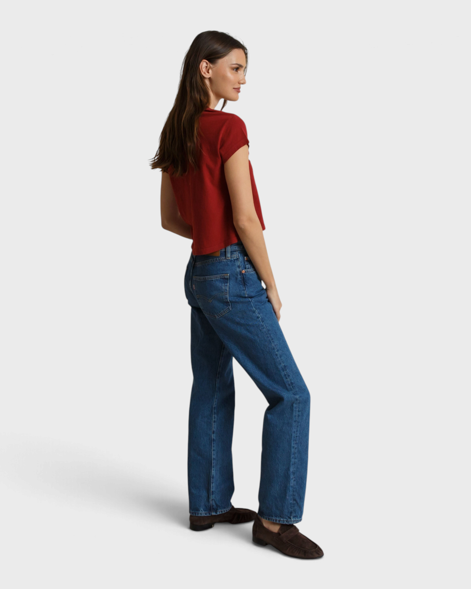 Model wearing a JONES + CO ruby red recycled cotton V-neck t-shirt paired with blue jeans and brown loafers