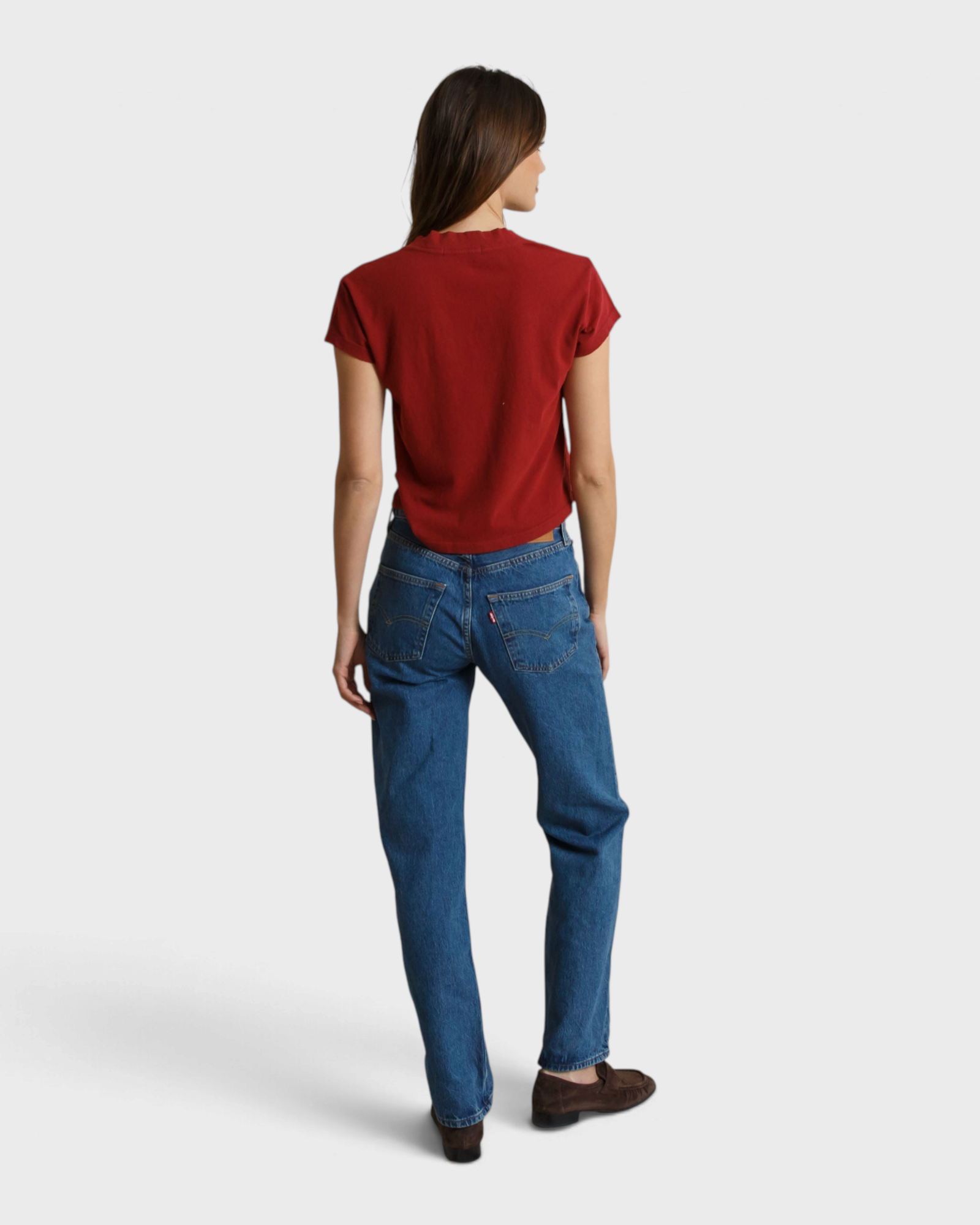 Back view of a woman wearing a JONES + CO ruby red recycled cotton V-neck t-shirt paired with blue jeans.