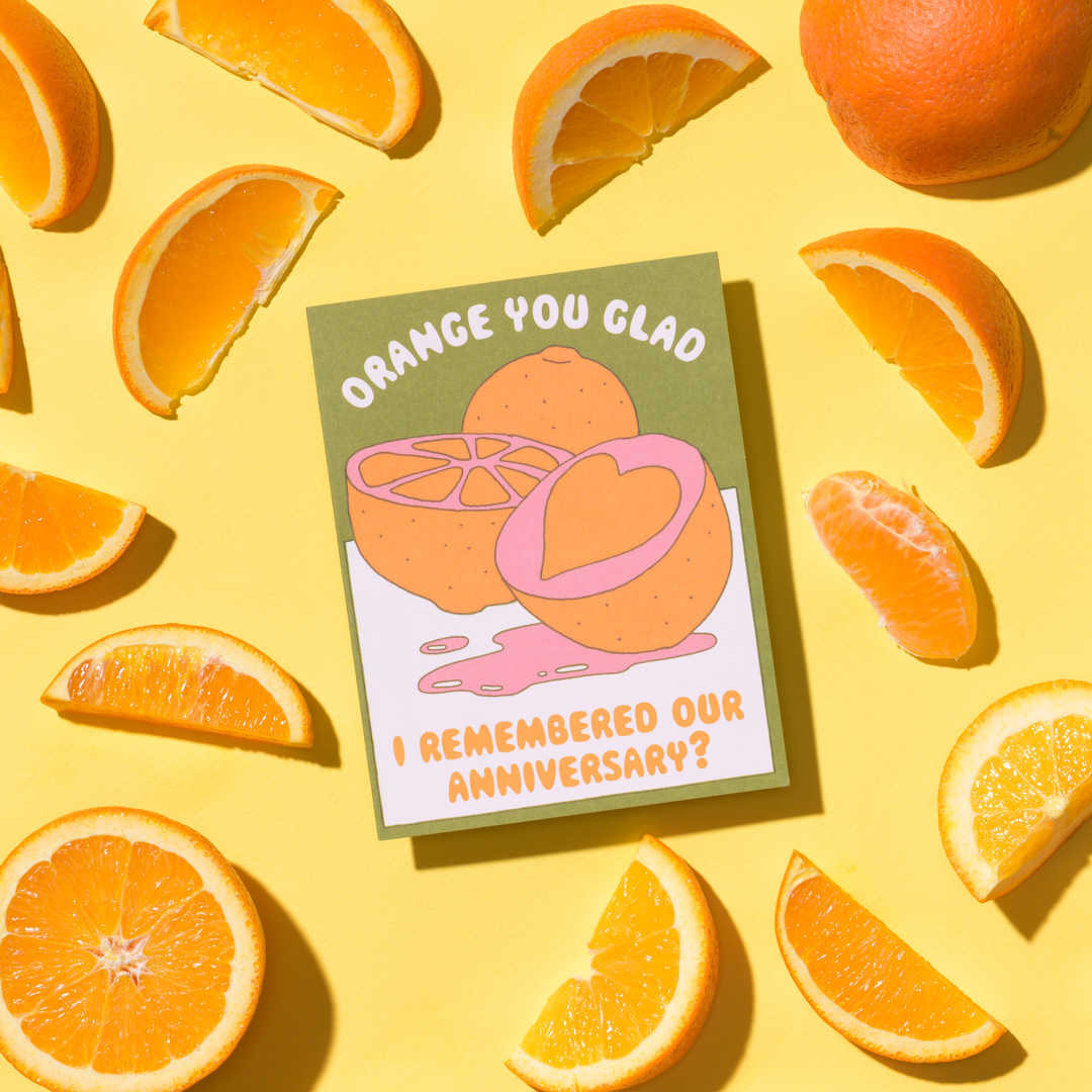 Card with orange design and text surrounded by oranges on a yellow background