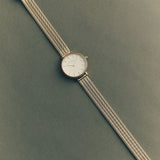 Silver watch with a textured band on a green background