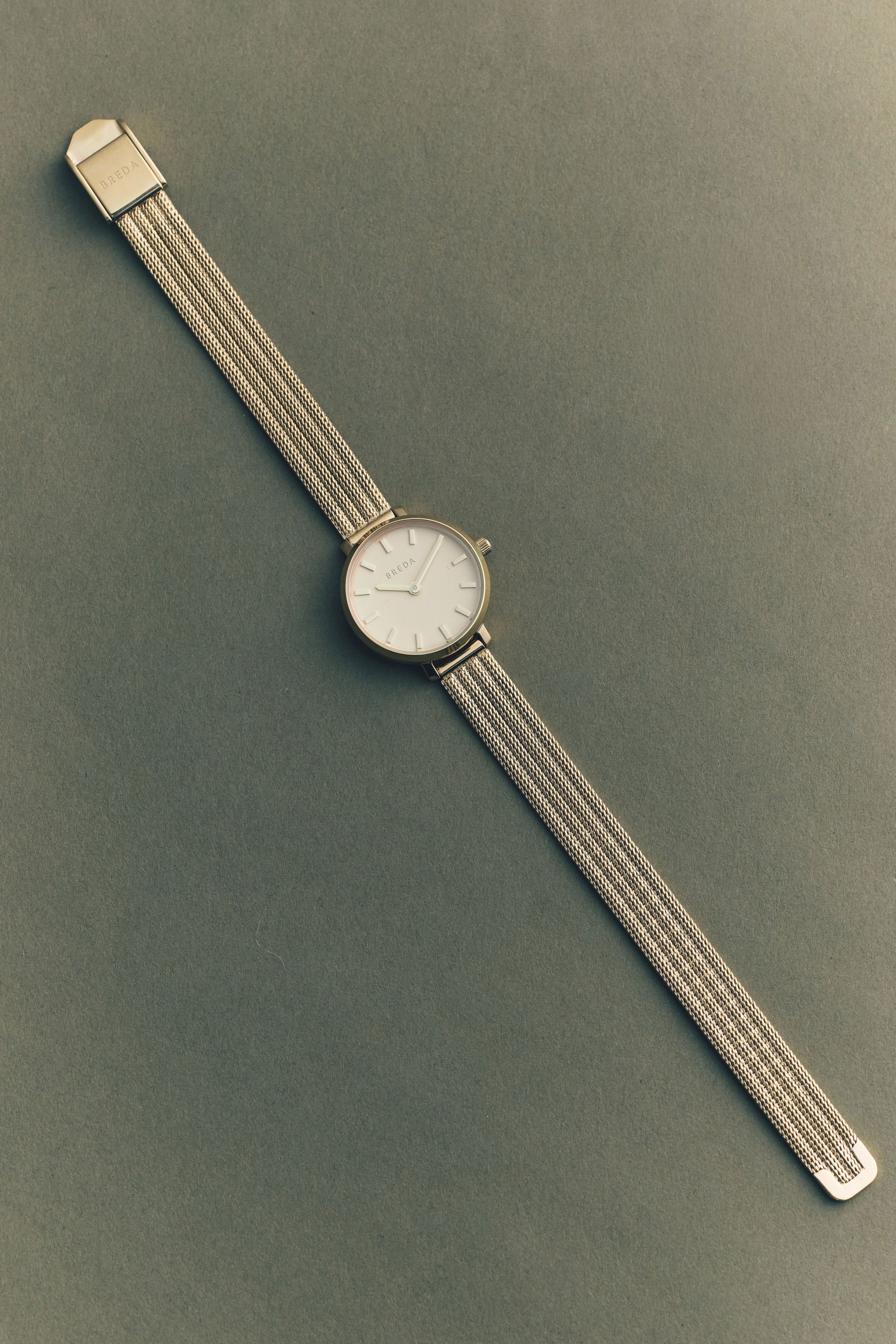 Silver watch with a textured band on a green background