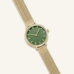 Gold watch with a green face on a white background