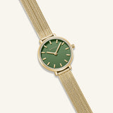 Gold watch with a green face on a white background