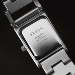 Close-up of a Breda watch with a metallic band on a black background