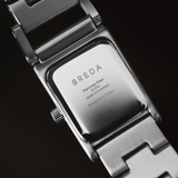 Close-up of a Breda watch with a metallic band on a black background