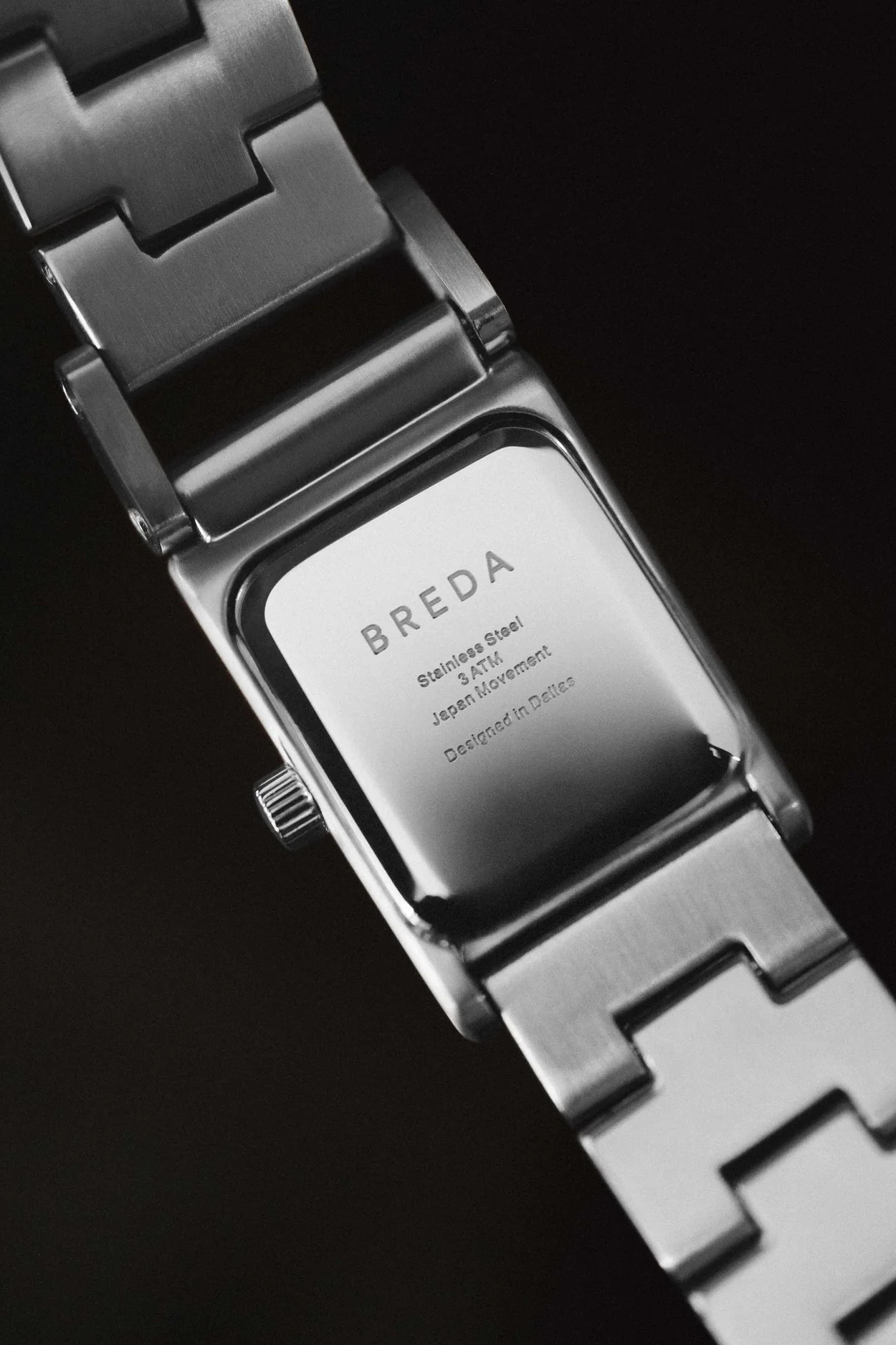 Close-up of a Breda watch with a metallic band on a black background