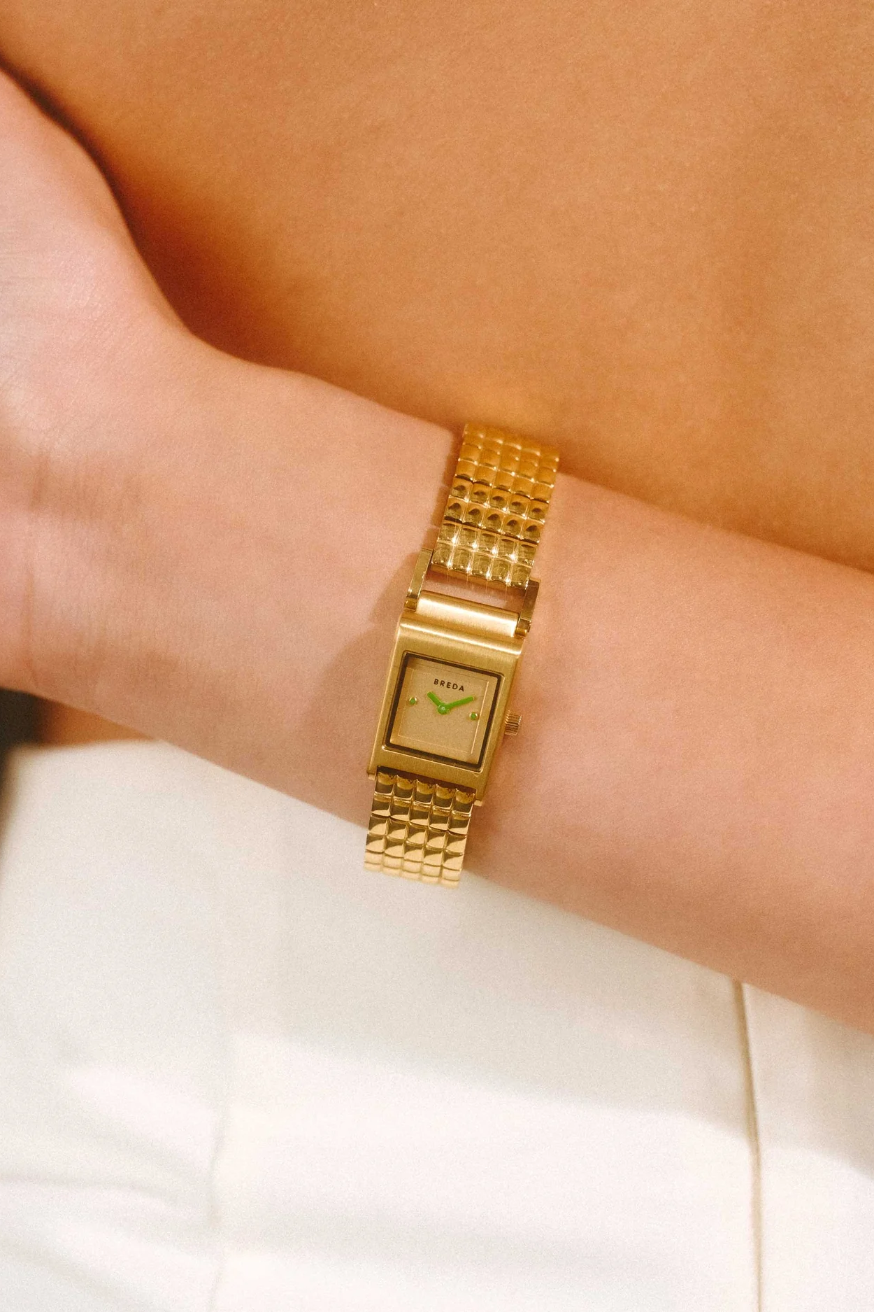 Gold wristwatch on a person's wrist with a blurred background