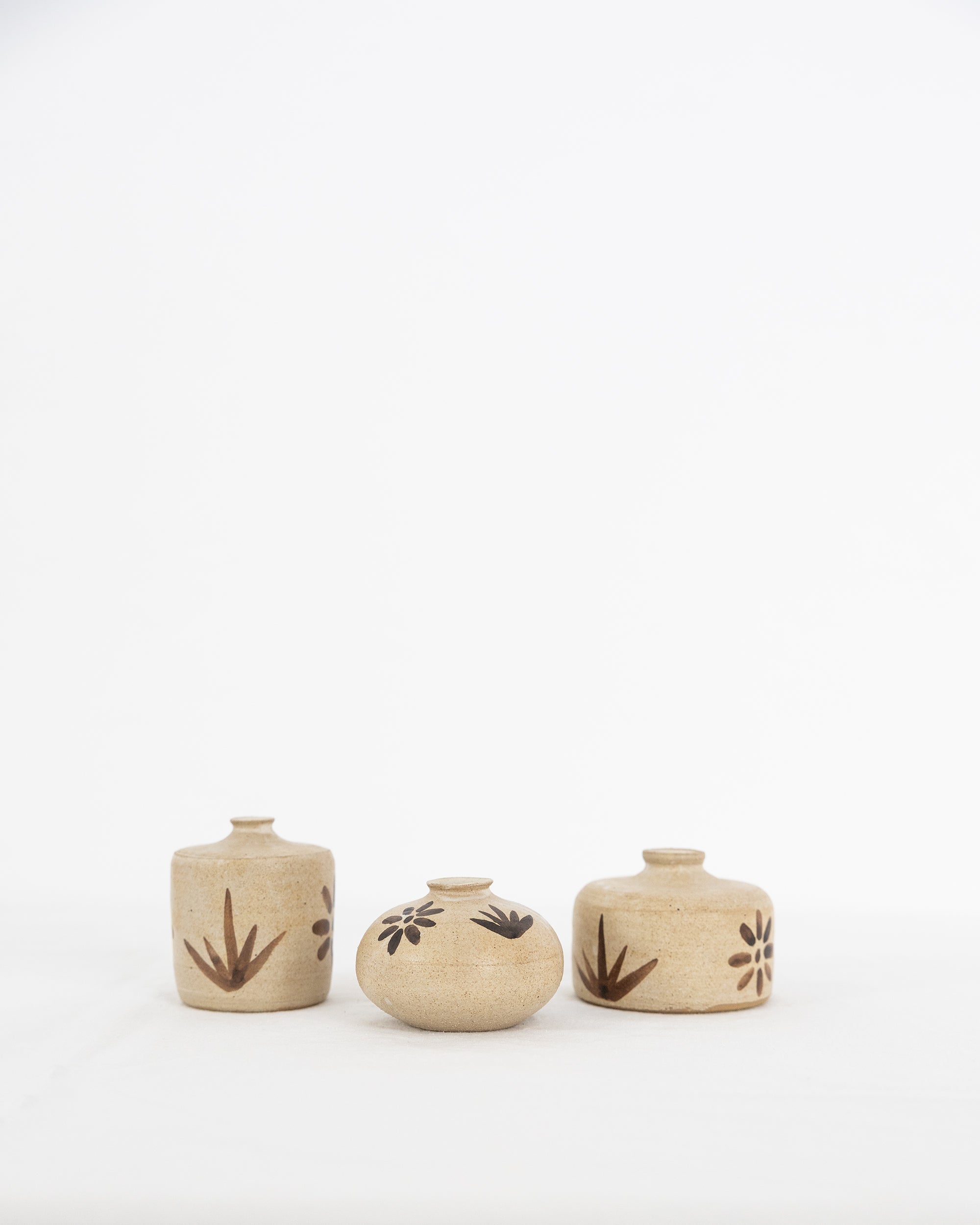 Three Bettina Chow olive leaf bud vases in natural clay with hand-painted leaf and flower motifs